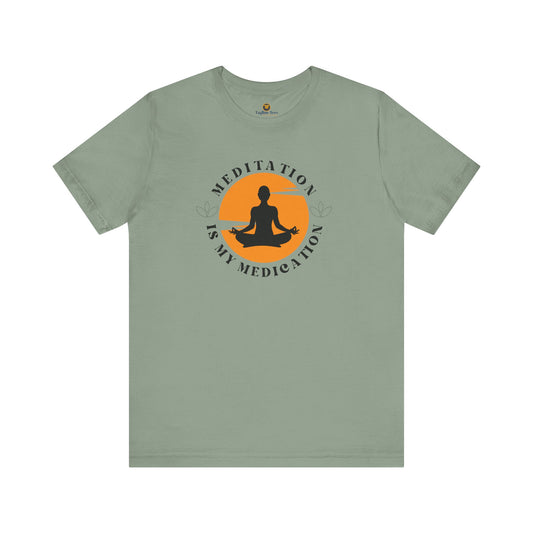 A sage green  t-shirt with a meditation graphic on a an orange retro sunset background